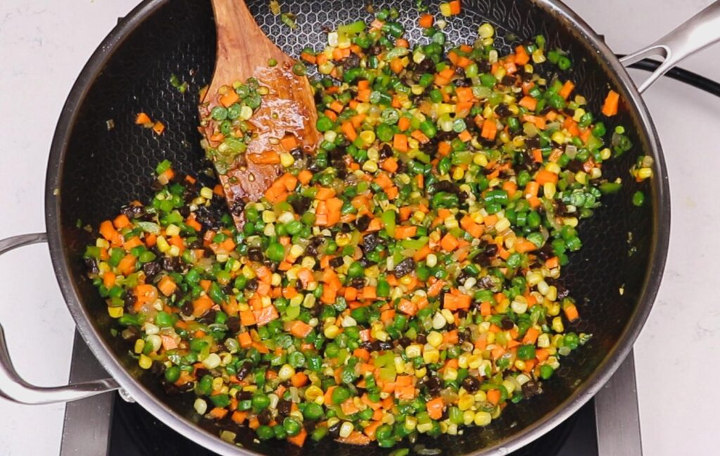 a pan with vegetables and a wooden spoon